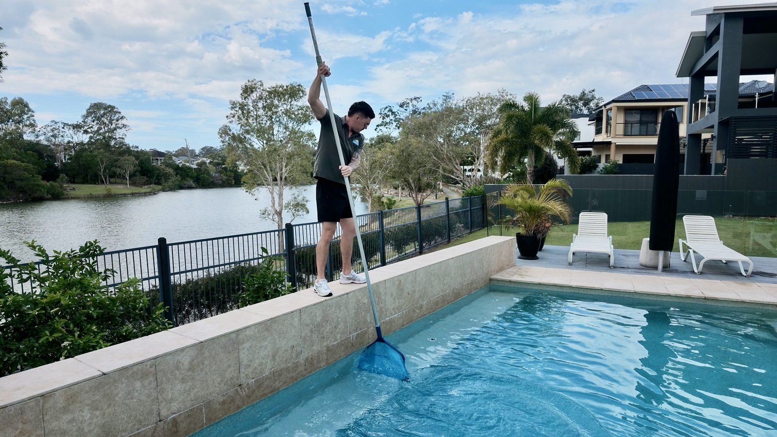 the poolboi skimming a pool with a net