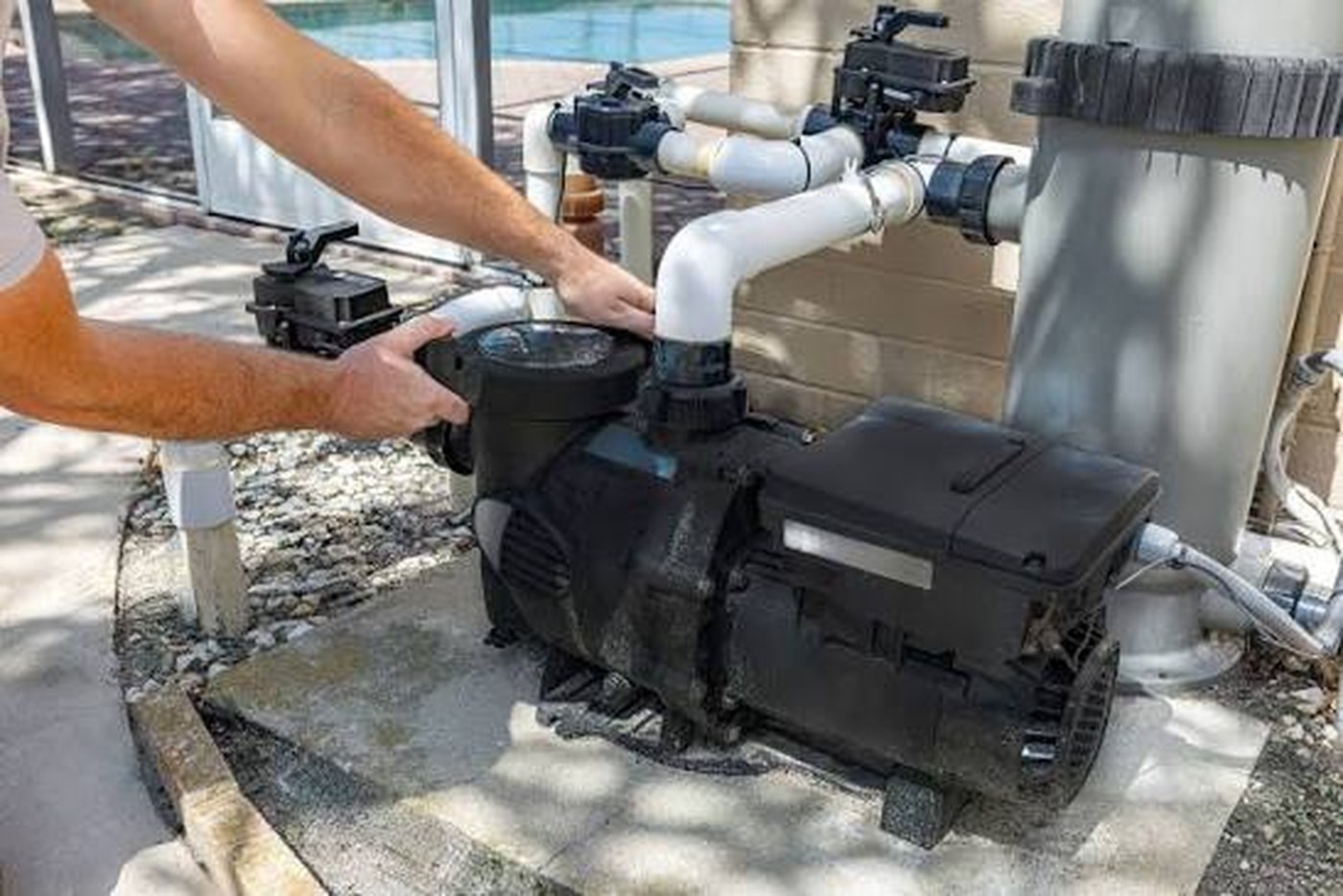 Technician servicing a pool pump and motor unit poolside